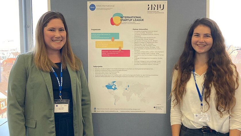 Sarah Leible (left) and Verena Mattes in front of a display wall with a poster about the project. (opens enlarged image)